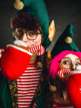 Dwoje aktorów w strojach elfów z dużymi pluszowymi, czerwonymi kubkami.