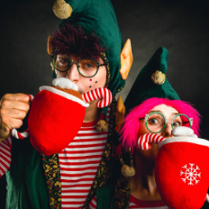 Dwoje aktorów w strojach elfów z dużymi pluszowymi, czerwonymi kubkami.