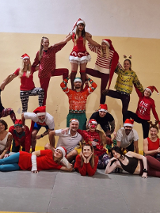 Grupa osób w świątecznych strojach tworzy piramidę ze swoich ciał.