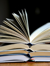 Zdjęcie trzech otwartych książek, ułożonych w stos.