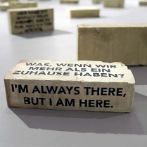 Instalacja artystyczna, betonowy klocek z napisami w różnych językach.