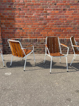 Na zdjęciu ustawione są cztery krzesła. Stoją one przy ceglanej ścianie.