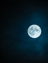 Rozświetlony księżyc w pełni na czystym nocnym niebie.