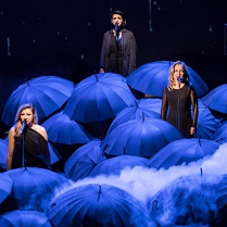 Aktorki na scenie w trakcie spektaklu, wokół nich parasolki