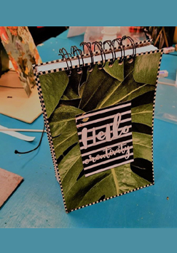 Na zdjęciu niebieski blat, na nim wykonany samodzielnie kolorowy notes