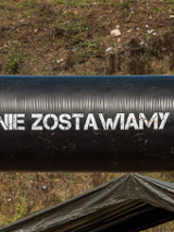 Grupa osób w strojach sportowych. Napis "Nigdy nie zostawiamy swoich". Obok przeszkody.