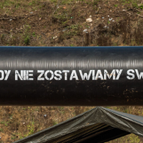 Grupa osób w strojach sportowych. Napis "Nigdy nie zostawiamy swoich". Obok przeszkody.