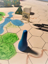 Gra planszowa, na niej długopis, pionek, kostka.