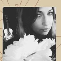 Kobieta za białym kwiatem, z tyłu gitara.