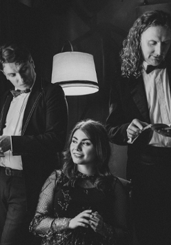 Dwójka mężczyzn trzyma książki. Między nimi siedzi kobieta.