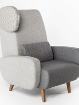 Na białym tle widać szary fotel Teddyi na drewnianych nóżkach.