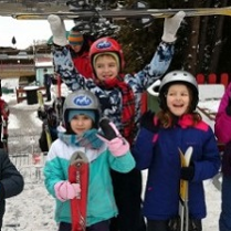 Grupa dzieci w zimowych kurtkach na dworze.