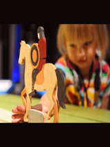 Figurka przedstawiająca rycerza na koniu, w tle rozmazana twarz dziecka.