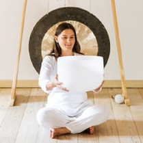 zdjęcie kobiety siedzącej po turecku; w rękach trzyma białą misę