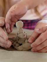 zdjęcie rąk osób lepiących z gliny