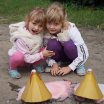 Dwie dziewczynki uśmiechające się i bawiące się w pisaku.