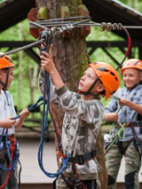 Dzieci w parku linowym, wspinające się po przeszkodach.