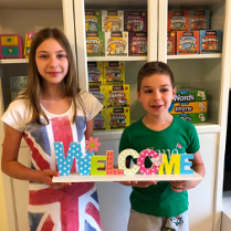 Dwójka dzieci trzymająca drewniany napis "welcome".