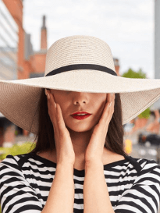 Zdjęcie popiersia szykownie ubranej kobiety w kapeluszu.