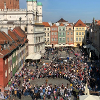 Zdjęcie zrobione podczas wcześniejszych świętowań. Duża grupa uczestników na płycie Starego Rynku w Poznaniu.