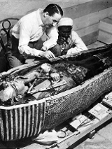 Zdjęie archeologa nad otwartym sarkofagiem.