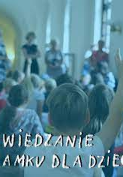 Grupa dzieci oraz osób dorosłych w zamkowym korytarzu. Na pierwszym planie siedzący tyłem do obiektywu chłopiec. Ma na sobie białą koszulkę i uniesioną prawą rękę - zgłasza się. Na zdjęcie nałożono filtr w kolorze błękitnym. U dołu biały odręczny napis "ZWIEDZANIE ZAMKU DLA DZIECI".