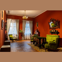 Wnętrze Muzeum: salon z antycznymi meblami i ciemnoczerwonymi ścianami.