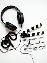 Zdjęcie słuchawek i tabliczki filmowej.