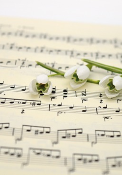 Zdjęcie zeszytu z nutami, na nim cztery przebiśniegi..