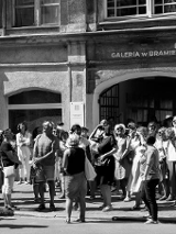 Czarno-białe zdjęcie wielu osób z widokiem Galerii w Bramie w tle.