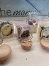 Poukładane na blacie świece w słoikach, ozdobione suszem.