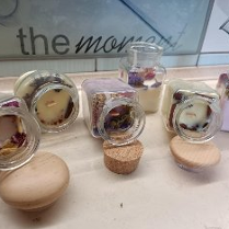 Poukładane na blacie świece w słoikach, ozdobione suszem.