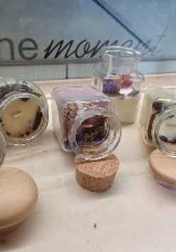 Poukładane na blacie świece w słoikach, ozdobione suszem.