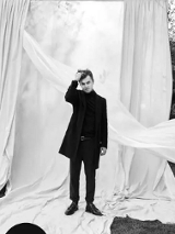 Czarno-białe zdjęcie mężczyzny na białym tle z tkanin rozwieszonych na dworze.