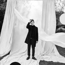 Czarno-białe zdjęcie mężczyzny na białym tle z tkanin rozwieszonych na dworze.