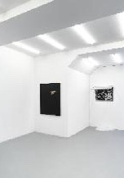 Zdjęcie z wystawy. Minimalistyczna biała przestrzeń galerii, na ścianach wiszą obrazy.