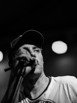 Czarno-białe zdjęcie popiersia mężczyny śpiewającego przez mikrofon.