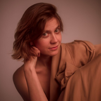 Kobieta w brązowych włosach, która podpiera głowę ręką.