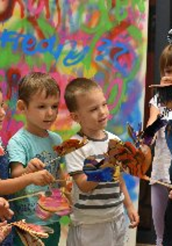 Na zdjęciu znajduje się grupka dzieci wraz z panią prowadząća warsztaty. Dzieci są w kółku i słuchają o czym opowiada prowadząca.