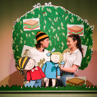 Zdjęcie przedstawiające dwóch aktorów na scenie z lalkami Gapiszona i Zuzi. W tle makieta drzewa.