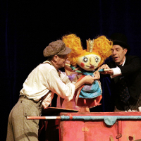 Zdjęcie aktorów z lalką w trakcie spektaklu.