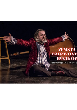 zdjęcie przedstawia aktora siedzącego na scenie, ubranego w wiśniową brokatową marynarkę, koszulę w błękitne pionowe paski oraz ciemne spodnie. Ręce ma rozłożone. Patrzy na widownię. Za aktorem po lewej stronie stoi wysoki stołek, a po prawej leży kontrabas.