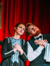 Mężczyzna i kobieta, stojący obok siebie z uniesionymi twarzami ku górze i złożonymi rękami na piersiach.