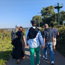 Grupa ludzi spacerująca wśród zieleni.