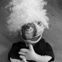 Zdjęcie szmacianej lalki z maską przypominającą kobietę, w peruce z kręconymi włosami.