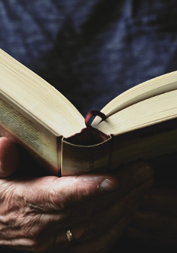 Zdjęcie, otwarta książka trzymana przez dłonie człowieka