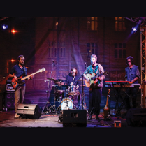 Czterech członków zespołu na scenie w trakcie koncertu.