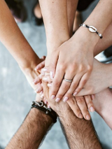 Ręce wielu osób, które nakładają się jedne na drugie.