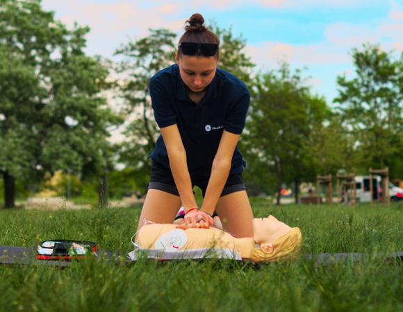 kobieta w trakcie udzielania pierwszej pomocy na fantomie, na trawie