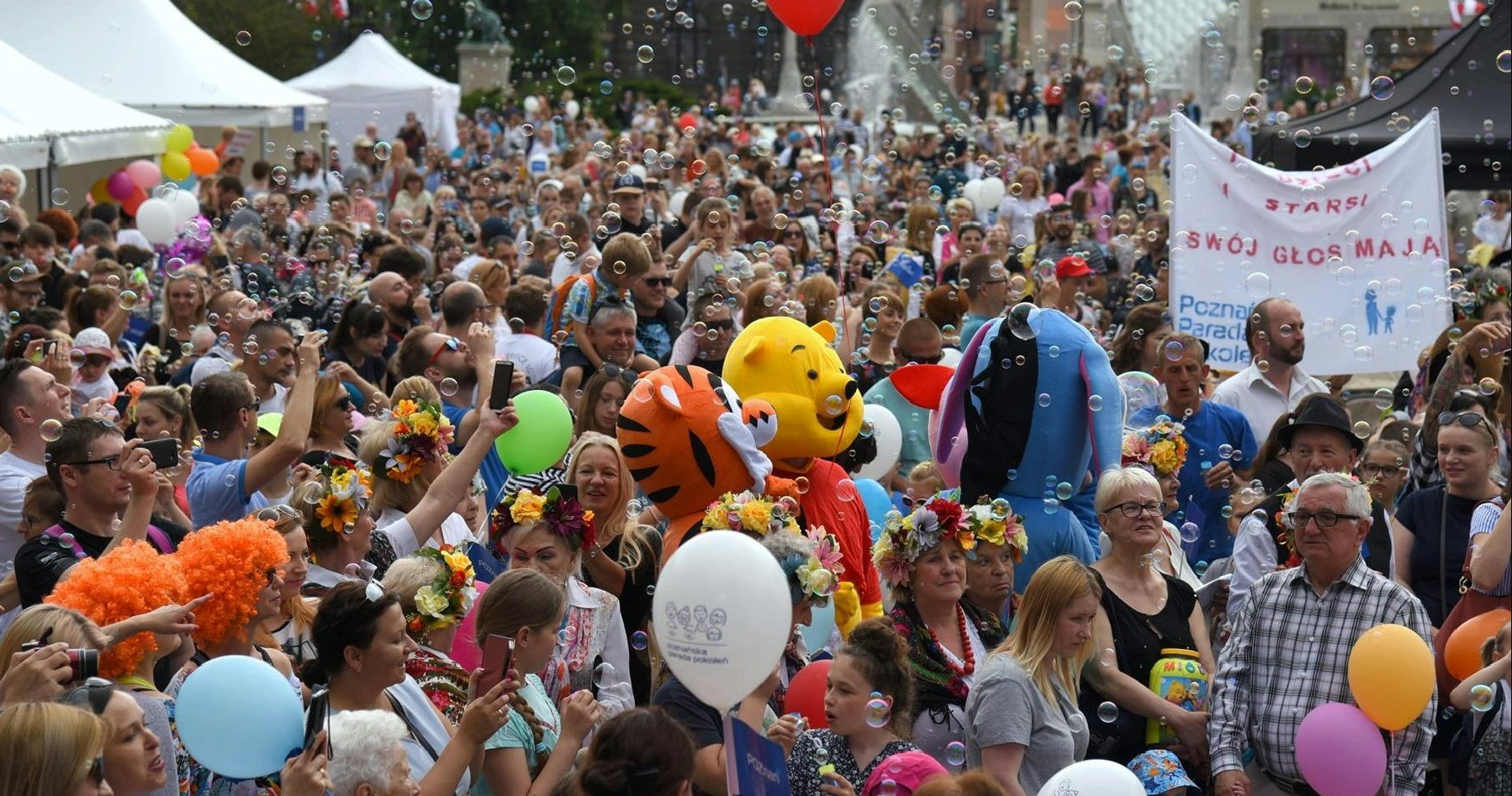 Poznańskie Dni Rodziny to radosne święto dla osób w każdym wieku Na zdjęciu tłum ludzi, widać kogoś w przebraniu misia, w powietrzu pełno baniek mydlanych